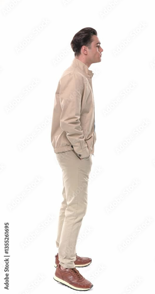 side view video of attractive young man in beige outfit standing in line, looking ahead and behind at the queue, nodding and making dislike gesture with the finger in front of white background side view video of attractive young man in beige outfit standing in line, looking ahead and behind at the queue, nodding and making dislike gesture with the finger in front of white background