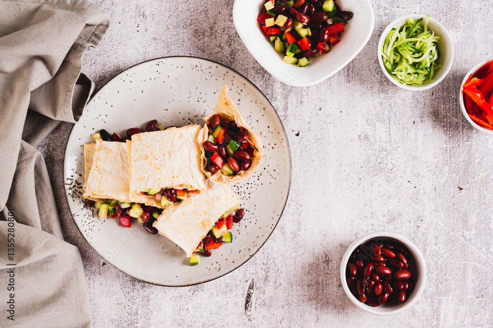 Salad of beans, cucumber and pepper in lavash rolls on a plate on the table top view