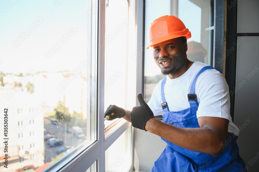 Young African Repairman In Overalls Installing Window Young African Repairman In Overalls Installing Window