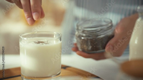 Wallpaper Mural A person adds spices to a glass of milk in a warm kitchen. This action highlights the process of enhancing flavor in a comforting beverage. It's a cozy moment focused on culinary creativity Torontodigital.ca
