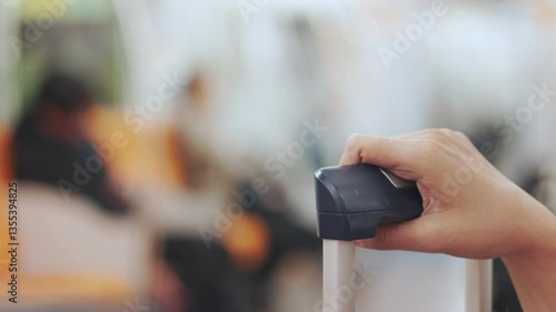 Wallpaper Mural Close up hand holding grips a suitcase handle on train, symbolizing travel and urban mobility. Selective focus highlights with blur background shows movement, transit, city life and modern commuting. Torontodigital.ca