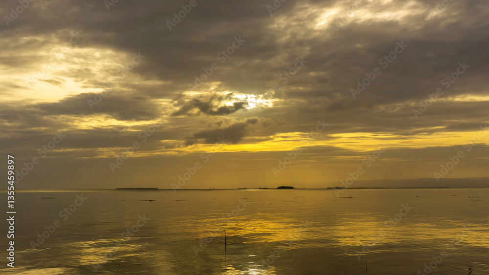 Fototapeta premium Sunset over calm waters with reflections and dramatic clouds