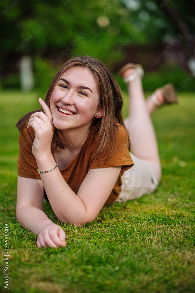 Carefree female relaxing on verdant lawn, gesturing skyward with bright smile during leisurely summer afternoon Carefree female relaxing on verdant lawn, gesturing skyward with bright smile during leisurely summer afternoon