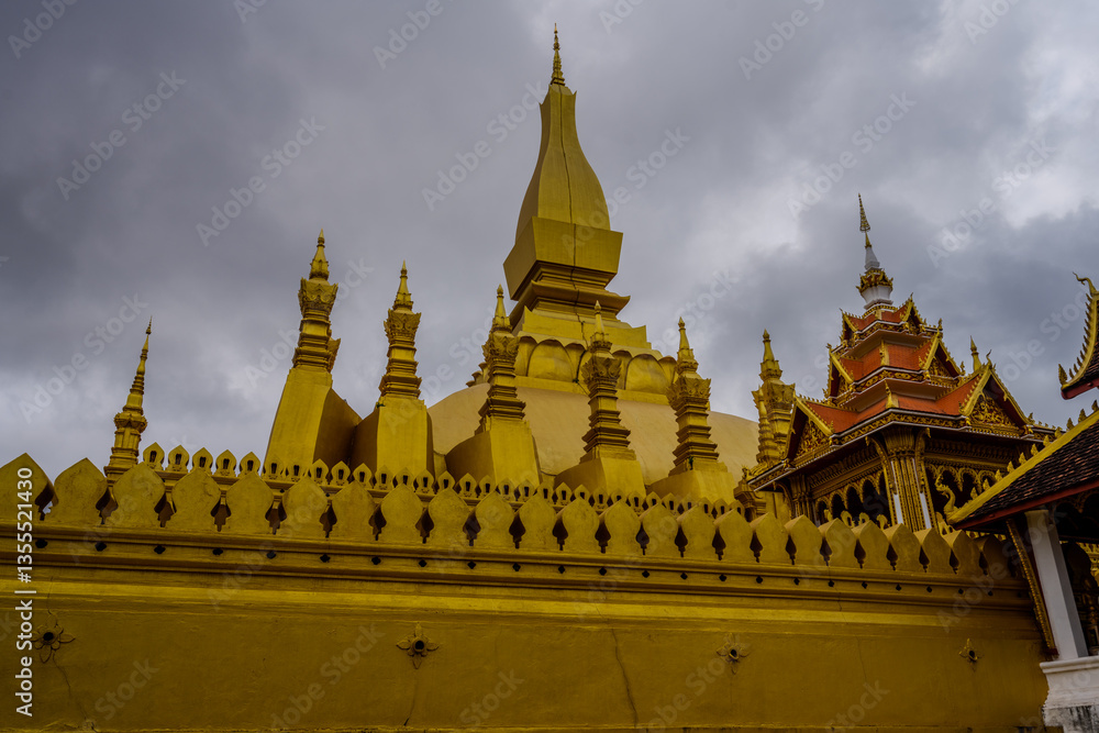 Naklejka premium Golden Stupa of Pha That Luang Temple in Vientiane, Laos under Overcast Sky – Iconic Buddhist Landmark and National Symbol