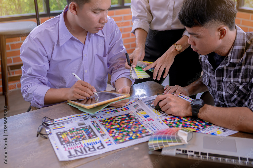 Fototapeta premium Team graphic designer checking print quality of media graphics proof print and color guides in printing industry. Selected focus
