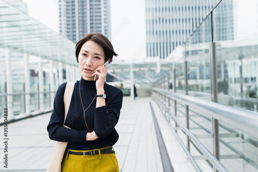 オフィス街を電話をしながら歩く30代日本人女性 オフィス街を電話をしながら歩く30代日本人女性