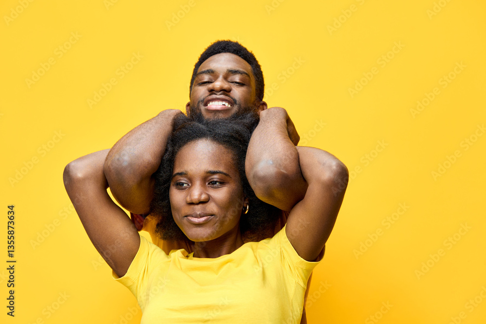Fototapeta premium Happy African couple enjoying playful moments against a bright yellow background, showcasing vibrant emotions and casual summer style in matching yellow outfits