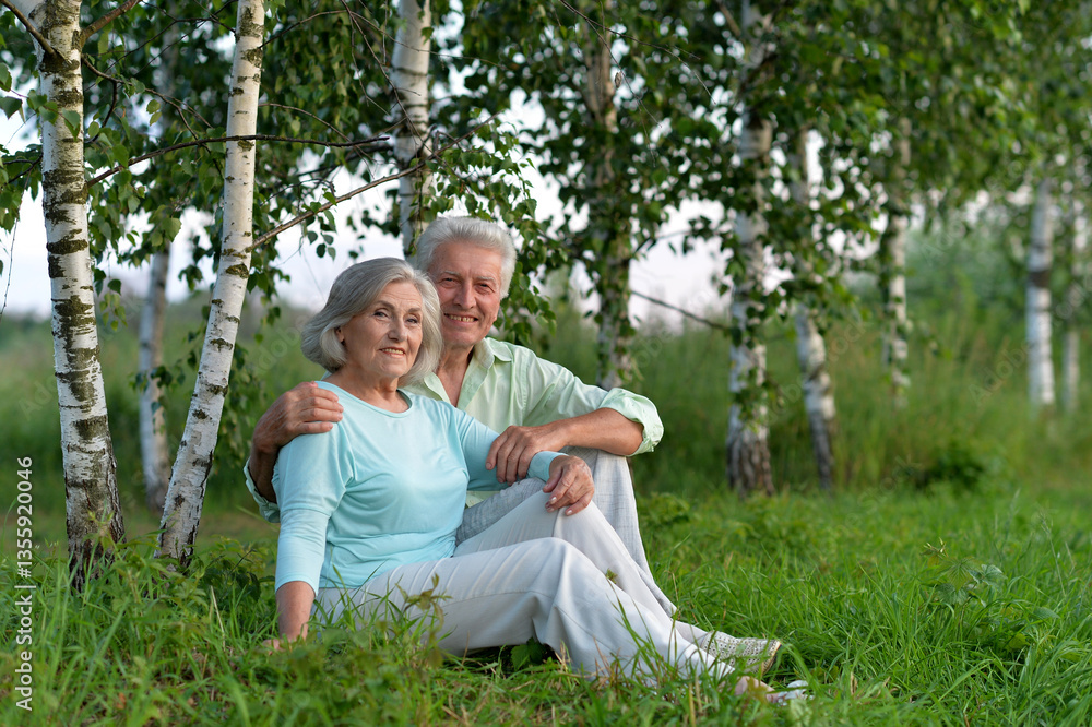 Happy senior couple sitting on grass in park