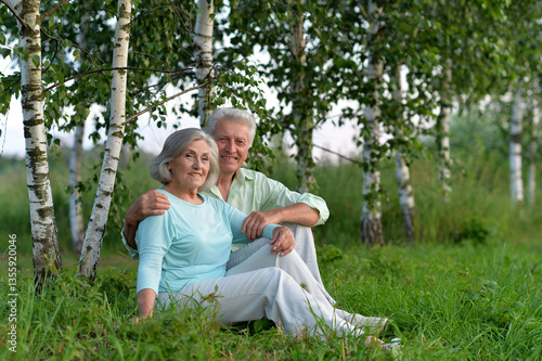 Obraz na płótnie Happy senior couple sitting on grass in park w salonie
