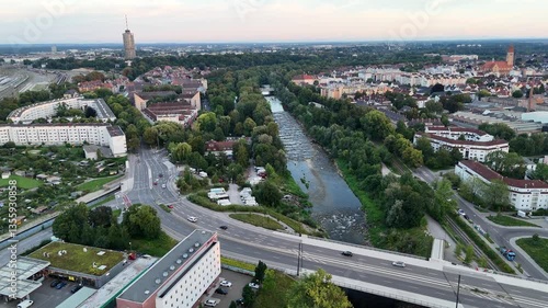Panorama flight along river Wertach with trees during sunset and hotel tower in the background in Augsburg, Germany