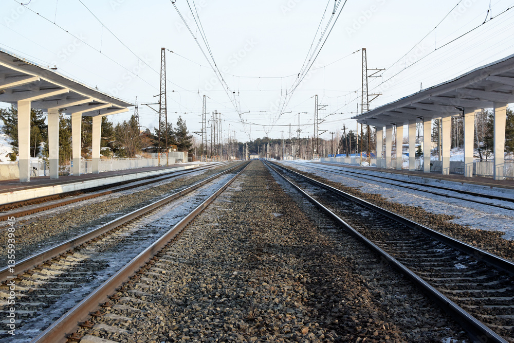 Empty railway track and empty passenger platform. Railway tracks stretch into the distance Empty railway track and empty passenger platform. Railway tracks stretch into the distance