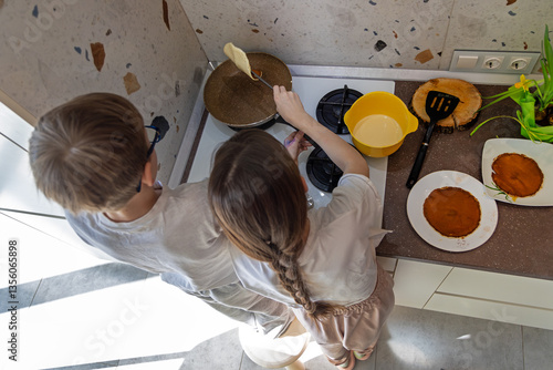 Φωτογραφία Children cooking pancakes together in kitchen