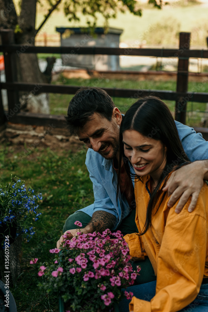 Naklejka premium Happy couple gardening together, taking care of flowers in their garden