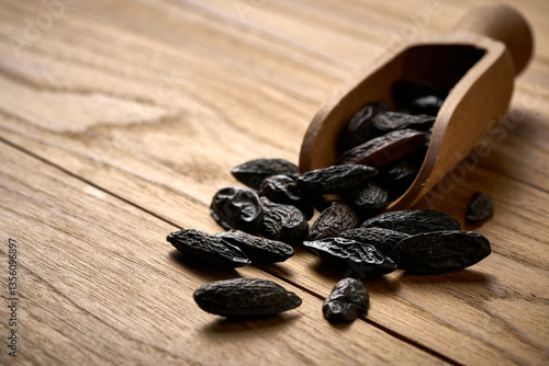 closeup pile of tonka bean on wooden table background in wood scoop with copy space