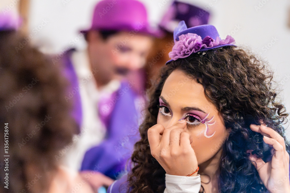 Fototapeta premium Young woman applying elaborate stage makeup, wearing a purple hat and costume, preparing for a theatrical performance