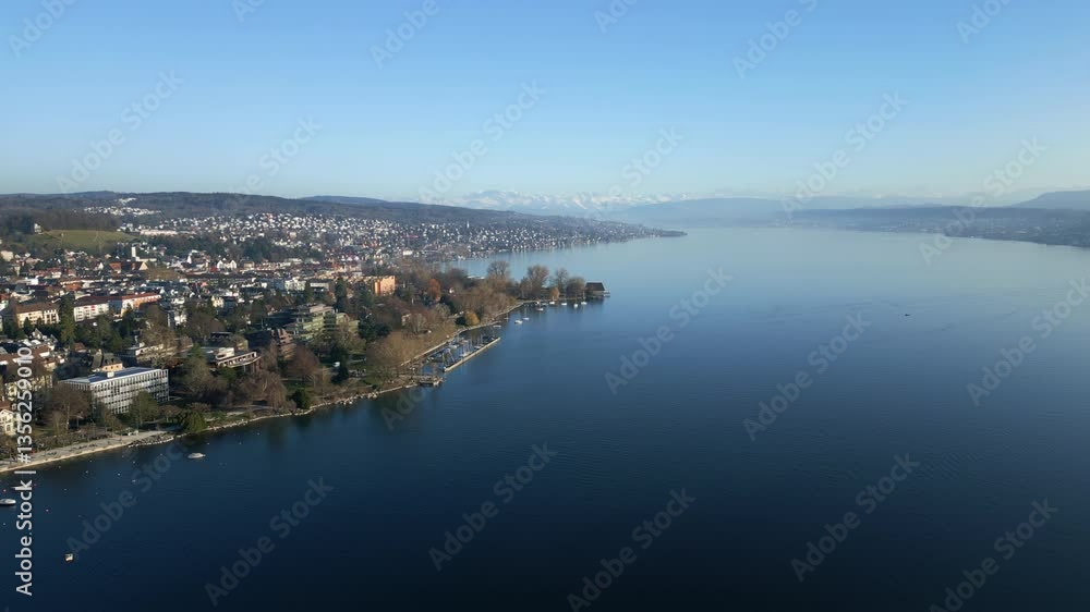 Aerial: Lake Zurich with shore, snowy mountains and blue sky during the day in Zurich, canton of Zurich, Switzerland, establishing drone shot Aerial: Lake Zurich with shore, snowy mountains and blue sky during the day in Zurich, canton of Zurich, Switzerland, establishing drone shot