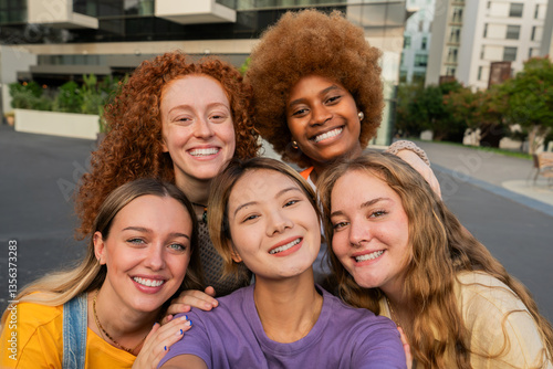 Group of joyful young women smiling brightly while posing together in a fun and lively atmosphere, showcasing their unique styles and strong friendships in a cheerful gathering moment