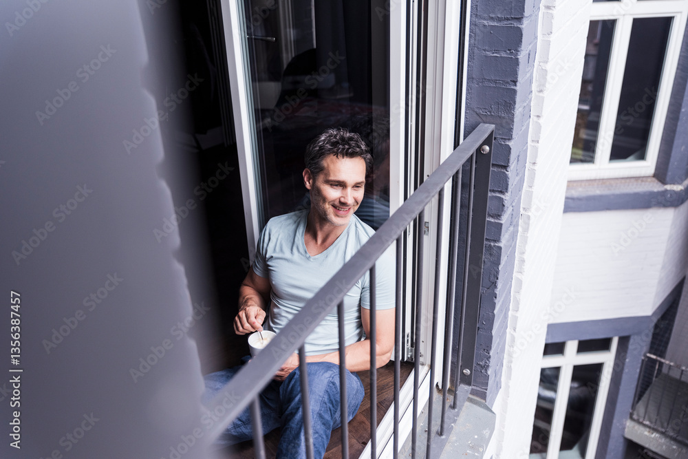 Man enjoying coffee on a balcony in the morning at home Man enjoying coffee on a balcony in the morning at home
