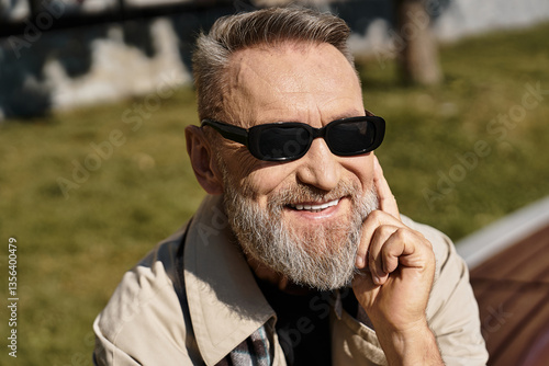 A handsome senior man confidently strolls through an urban landscape, in chic attire.