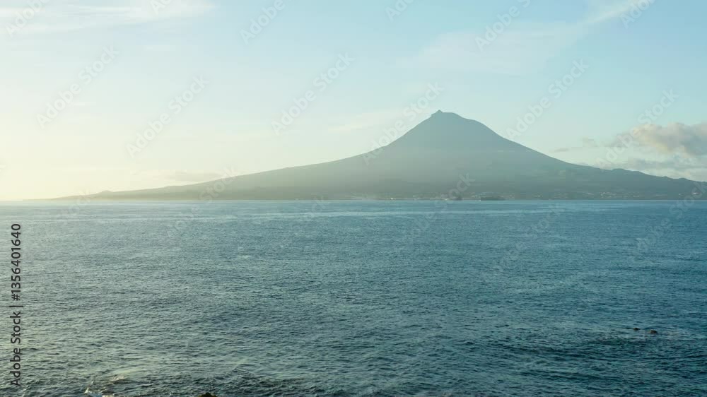 A captivating scene of morning fog gently rolling over the landscape, with Pico Island’s towering volcanic mountain rising in the background, showcasing the mystical beauty of this volcanic island. A captivating scene of morning fog gently rolling over the landscape, with Pico Island’s towering volcanic mountain rising in the background, showcasing the mystical beauty of this volcanic island.