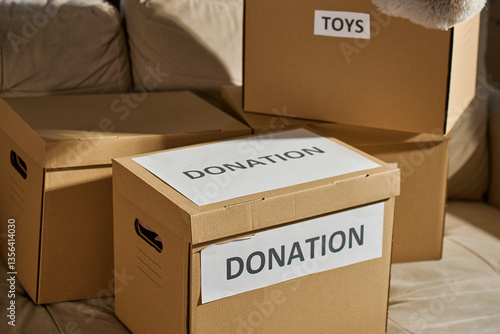 Donation boxes in living room. Packed cardboard boxes full of clothes and toys on couch. Concept of charity, social care and volunteering