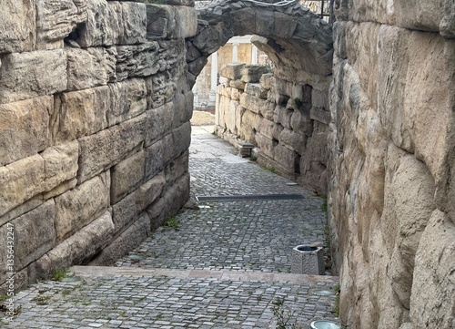 cobbled street with archway leading to amphitheater