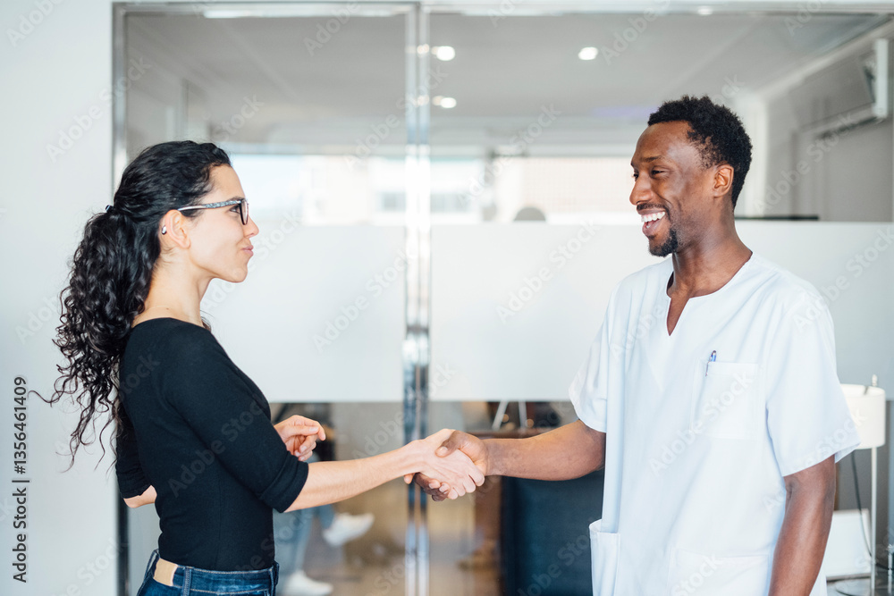 Smiling dentist shaking hands with patient in dental surgery Smiling dentist shaking hands with patient in dental surgery