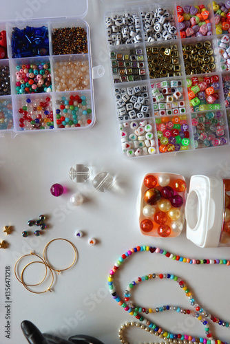 Hand figurine, colorful friendship bracelets, necklaces, various beads and DIY supplies on the table. Making jewelry at home. Flat lay.