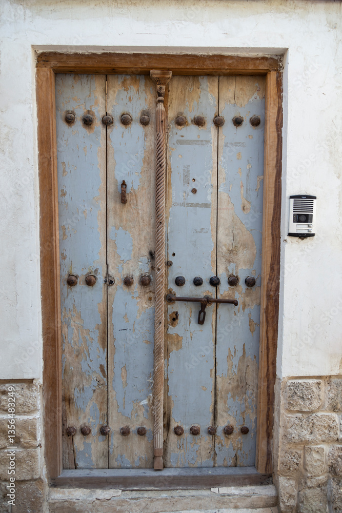 Weathered wooden door set in a traditional stone wall, showcasing the historic charm of old Bushehr’s architecture. Weathered wooden door set in a traditional stone wall, showcasing the historic charm of old Bushehr’s architecture.