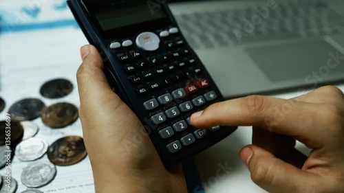 Financial Calculations with Calculator and Coins, Person using a calculator with coins and documents on a desk