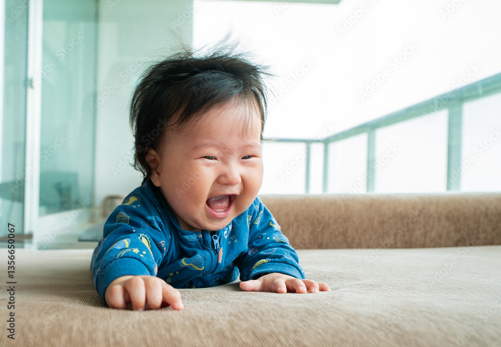 A baby is smiling and laughing while laying on a couch A baby is smiling and laughing while laying on a couch