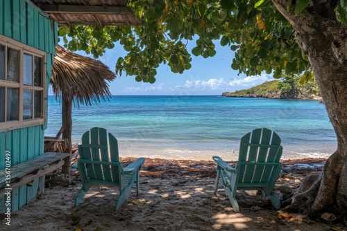 Relaxing chairs on a sandy beach with clear blue water and lush greenery in the background at a tropical location