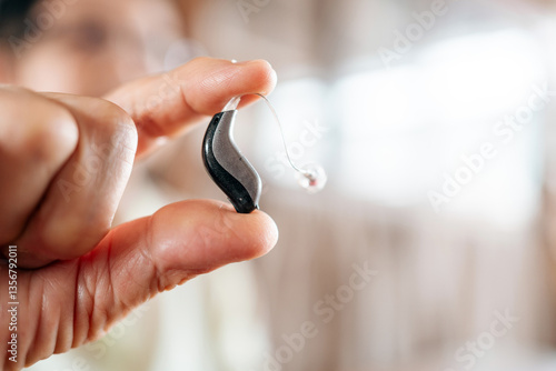 Foto Close-up of a senior hand holding a modern hearing aid device, showcasing advanced technology for improved sound amplification and hearing support