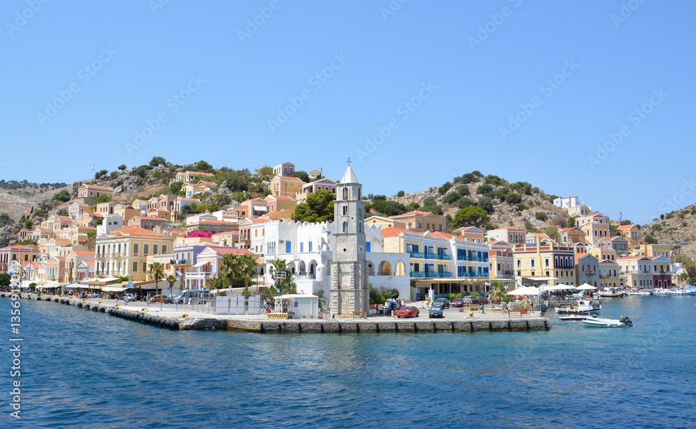 Naklejka premium Symi Island harbor view with colorful houses and boats on a sunny day