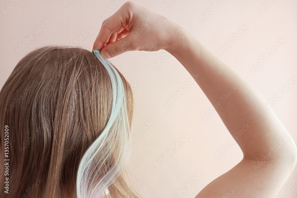 Naklejka premium Caucasian blonde woman attaching artificial hair strand to her hair. Back view. Disposable background.