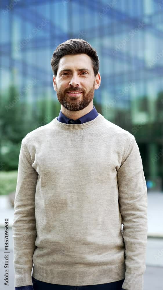 Vertical video. Confident smiling businessman standing on city street. Mature male professional in urban environment in casual attire. Outdoor portrait adult entrepreneur near modern office building Vertical video. Confident smiling businessman standing on city street. Mature male professional in urban environment in casual attire. Outdoor portrait adult entrepreneur near modern office building