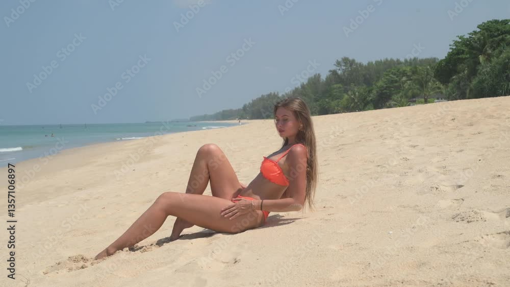 the girl is sexually lying on the beach and sunbathing. Beach with palm background, sunny day, smiling, seating on the sand the girl is sexually lying on the beach and sunbathing. Beach with palm background, sunny day, smiling, seating on the sand