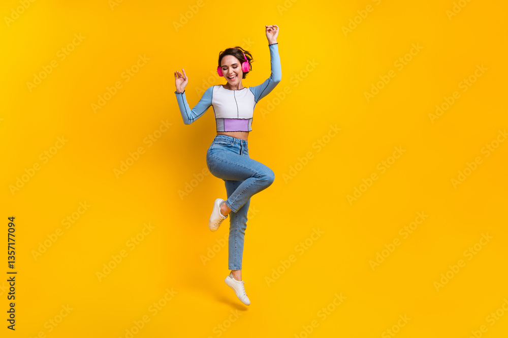 Full size photo of overjoyed girl jump enjoy favorite song empty space isolated on yellow color background Full size photo of overjoyed girl jump enjoy favorite song empty space isolated on yellow color background