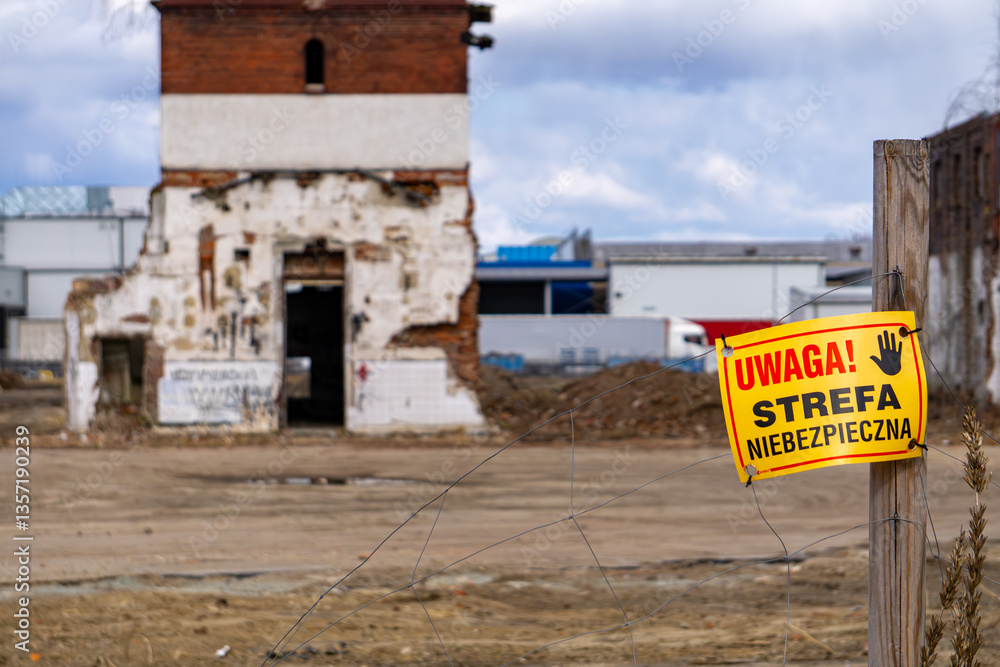 old crumbling buildings in the city. buildings prepared for demolition. fence with inscription in Polish: caution danger zone. construction site. old crumbling buildings in the city. buildings prepared for demolition. fence with inscription in Polish: caution danger zone. construction site.
