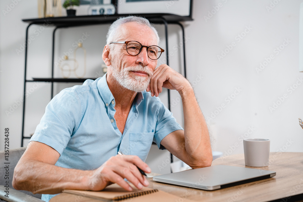 Fototapeta premium Portrait of happy handsome mature gray-haired caucasian freelancer or manager, stylishly dressed, sitting at the table, taking a break from work, dreaming about vacation, looking away, hands joining