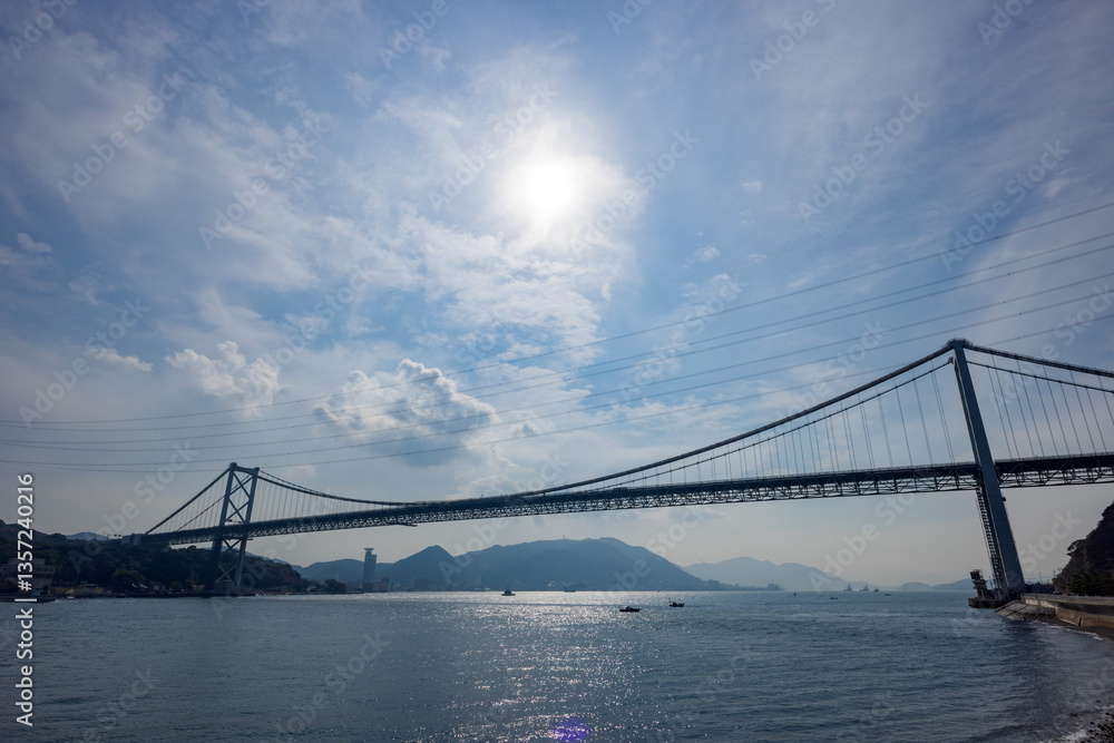 Fototapeta premium 青空と太陽光に照らされる関門橋と光る海面の風景