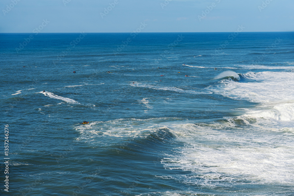 Fototapeta premium People surfing on surfboard in the ocean. Nazare, Portugal