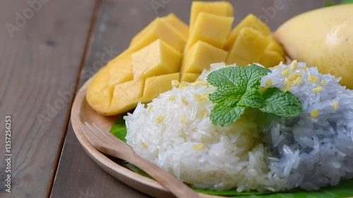 Put Crispy Mung bean on Coconut Flavored Sticky Rice with Ripe Mango on wood dish, Popular Thai desserts on summer.Slow motion