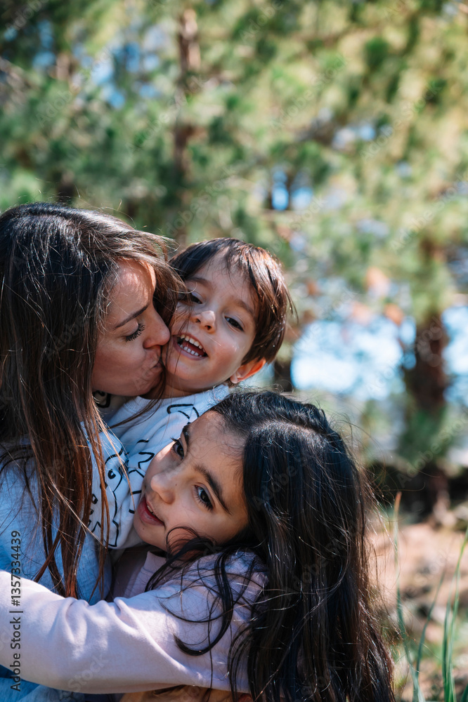 A woman is hugging two children, one of whom is wearing a shirt with a cat on it. The children are smiling and seem to be enjoying the moment. The woman is likely a mother or a close family member A woman is hugging two children, one of whom is wearing a shirt with a cat on it. The children are smiling and seem to be enjoying the moment. The woman is likely a mother or a close family member