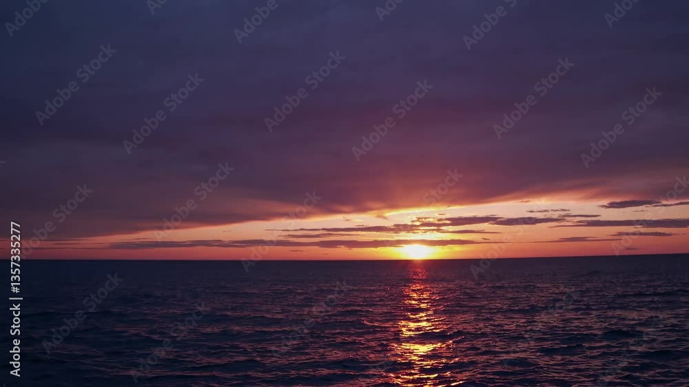 A serene sunset over the ocean captured from a low-angle, wide-shot video, showcasing vibrant hues of orange and purple in the sky and water. Live desktop wallpaper. A serene sunset over the ocean captured from a low-angle, wide-shot video, showcasing vibrant hues of orange and purple in the sky and water. Live desktop wallpaper.