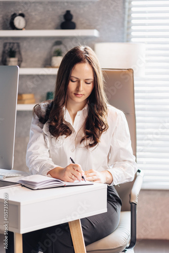 Focused businesswoman writing notes at a modern office desk