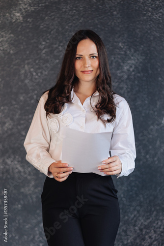 Confident businesswoman holding a document, standing against a dark modern background