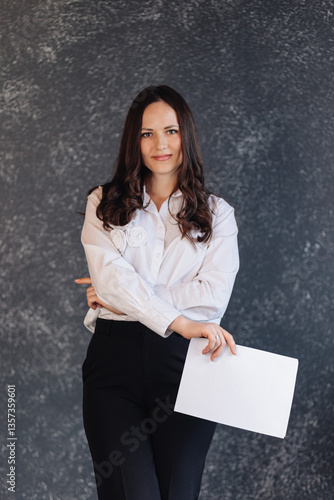 Confident businesswoman holding a document, standing against a dark modern background