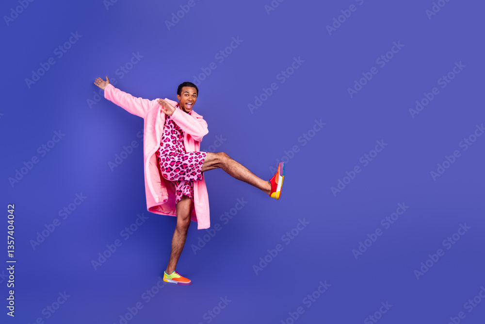 Obraz premium Young man in stylish pink leopard outfit on vibrant purple background showing playful and funky vibes