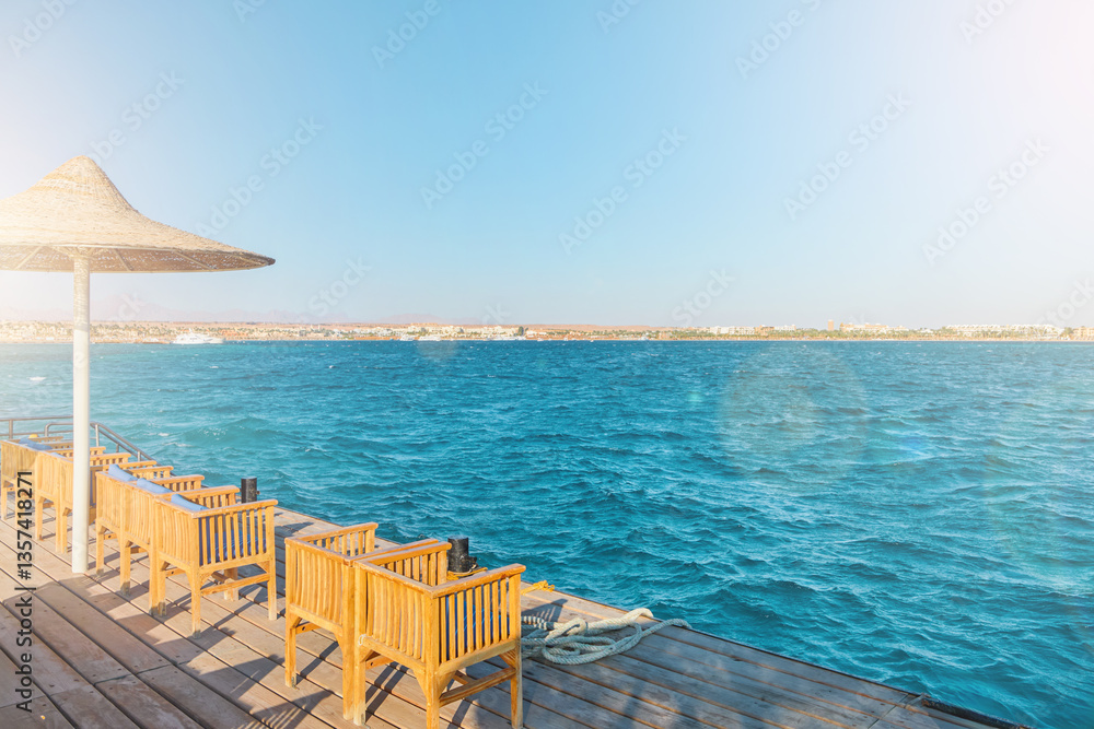 Obraz premium Wooden pier on sea stretching into distance beyond horizon on sunny summer day. Vacation and Travel Concept.